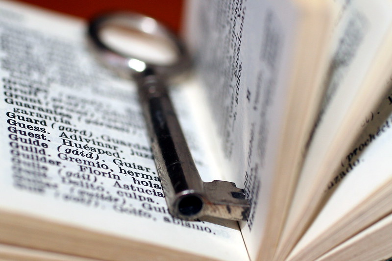 Diccionario abierto al azar con una lupa encima de sus páginas.